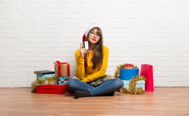 Chica celebrando las fiestas navideñas sosteniendo una tarjeta de crédito.