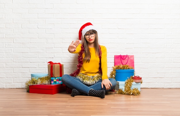 Chica celebrando las vacaciones de navidad haciendo gesto de parada con su mano