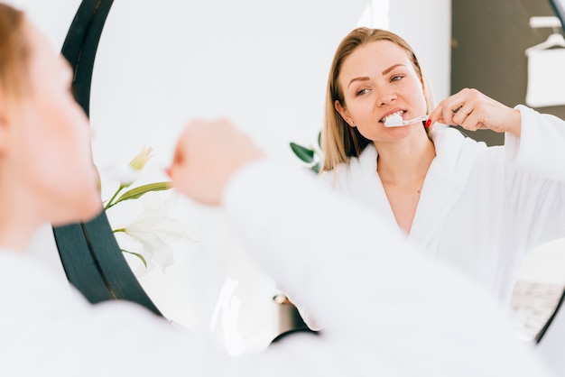 Foto chica cepillándose los dientes en el baño