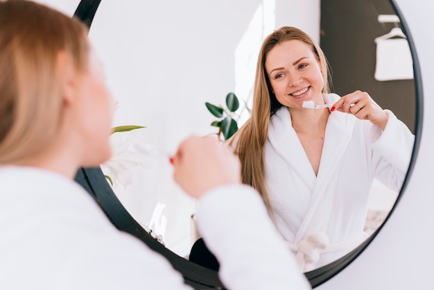 Foto chica cepillándose los dientes en el baño