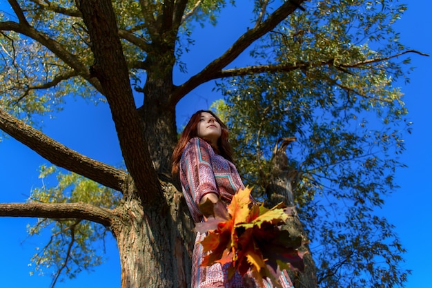 La chica de cerca en el follaje de otoño