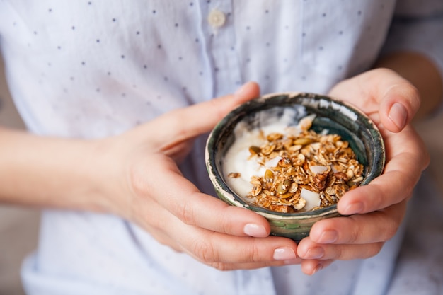 Chica con cereal de yogur con nueces, semillas de calabaza, avena en un recipiente