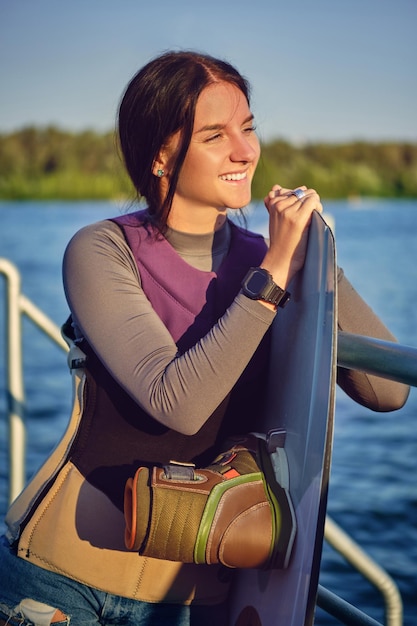 Chica en un chaleco deportivo especial de cuello alto gris y reloj negro está mirando hacia otro lado y sonriendo mientras posi