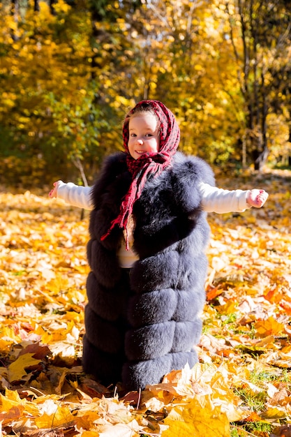 Chica en el chaleco de mamá en el parque otoño