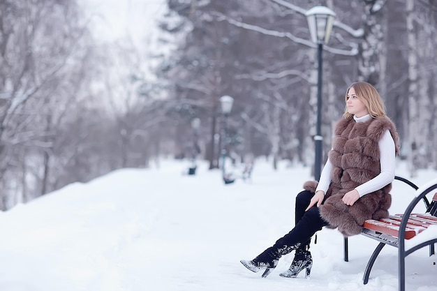 chica en un chaleco de piel camina en el exterior de invierno / modelo joven adulto en piel de ropa de invierno