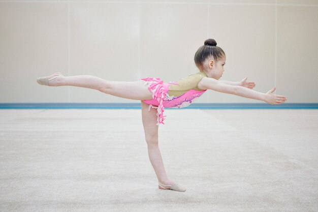 Una chica en chándal hace un estiramiento. Gimnasta entra en deportes. Concepto de estilo de vida saludable, uniformes deportivos, Copa del Mundo, gimnasio, ropa especializada, uniformes.