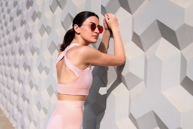 Chica en un chándal rosa se encuentra cerca de la pared