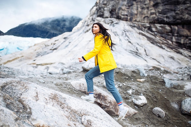 La chica de una chaqueta amarilla corriendo al aire libre en las montañas de Noruega Mujer activa disfruta de la libertad