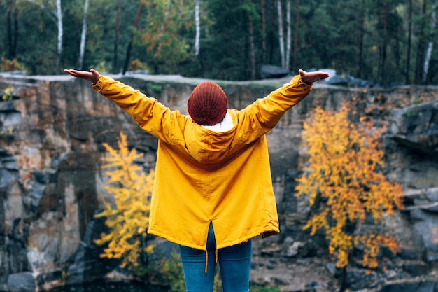 Chica en una chaqueta amarilla y un sombrero marrón Un paseo por las montañas de otoño Caminante camina en las rocas junto al agua en el Cañón Korostyshiv