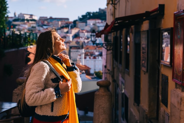 Foto chica con una chaqueta y una bufanda amarilla cerró los ojos caminar por la calle