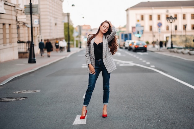 Una chica con chaqueta y cabello largo camina por la ciudad vieja.