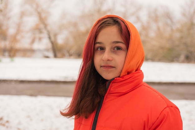 Una chica con una chaqueta cálida de color naranja brillante. Chica con una chaqueta naranja en tiempo de nieve. Chica adolescente en invierno