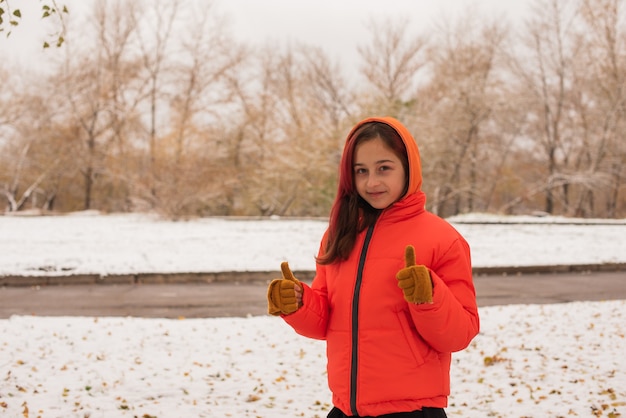 Una chica con una chaqueta cálida de color naranja brillante. Chica con una chaqueta naranja en tiempo de nieve. Chica adolescente en invierno