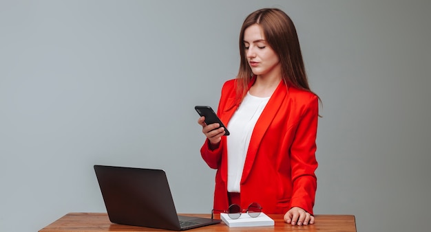 Chica de chaqueta roja escribiendo un mensaje en el teléfono