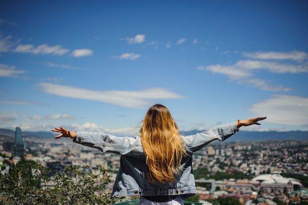 Foto chica en chaqueta vaquera mirando una vista increíble de la ciudad