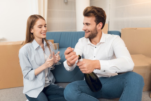 Chica y chico celebran mudarse al apartamento con champán.