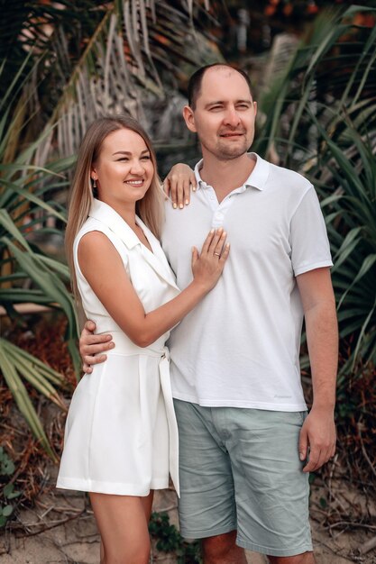 Una chica y un chico enamorado posan en la playa contra el fondo de las palmeras