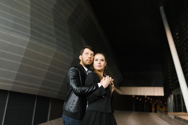 Chica y chico enamorado de la ropa oscura en el fondo de un edificio geométrico oscuro