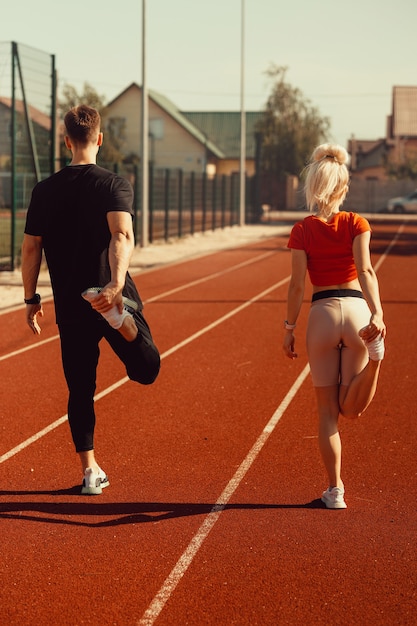 Chica y un chico haciendo un calentamiento antes de los ejercicios deportivos en el estadio de la escuela.