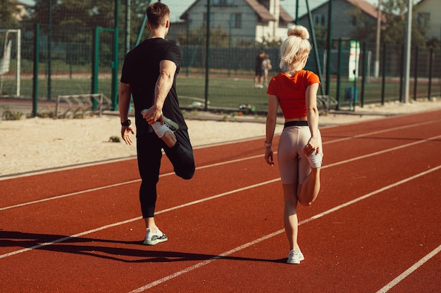 Chica y un chico haciendo un calentamiento antes de los ejercicios deportivos en el estadio de la escuela.