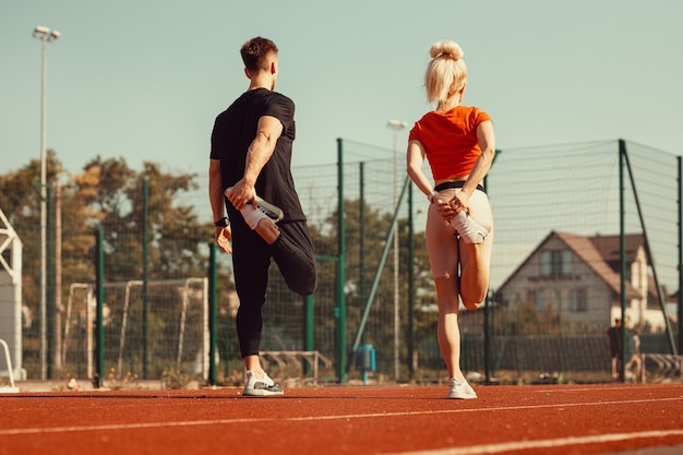 Chica y un chico haciendo un calentamiento antes de los ejercicios deportivos en el estadio de la escuela.