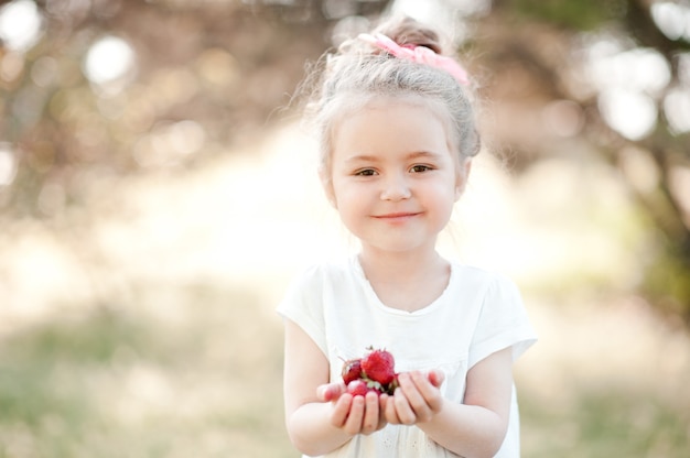 Chica chico lindo comiendo fresas al aire libre