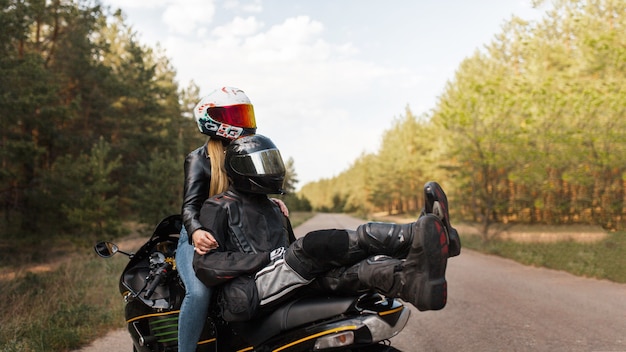 Chica y chico motociclista en una motocicleta deportiva en cascos sentados juntos y abrazándose sobre un fondo borroso con espacio de copia