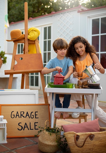 Foto chica y chico de tiro completo en una venta de garaje