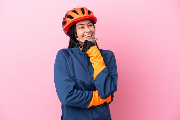 Chica ciclista adolescente aislada sobre fondo rosa feliz y sonriente