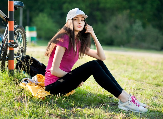 Chica ciclista descansa sentada en el suelo