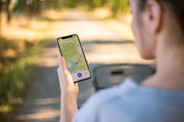 Foto chica ciclista mira un mapa en su teléfono y traza una ruta para un viaje para un navegador gps