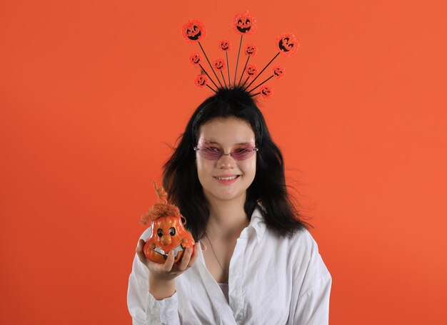 chica con una cinta para la cabeza de Halloween en un fondo naranja