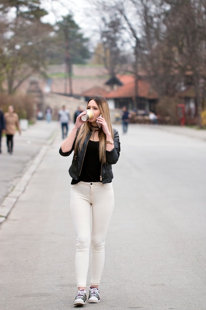 Chica de ciudad con teléfono inteligente y taza de café