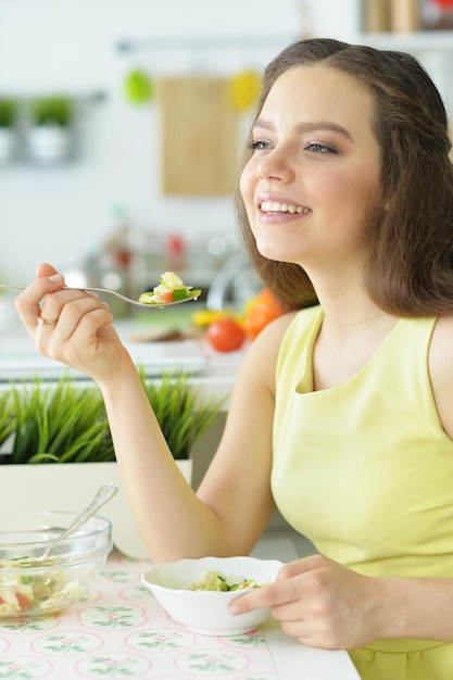 Chica en la cocina comiendo una ensalada