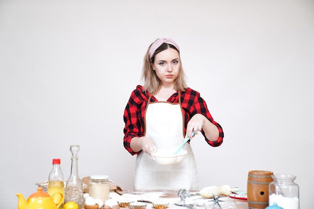 Chica cocinando, chica en delantal, chica divertida manchada con harina, chica revolviendo la masa