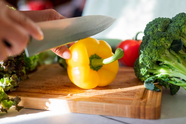 Foto chica cocinera en la cocina corta pimentón rojo con verduras con un cuchillo