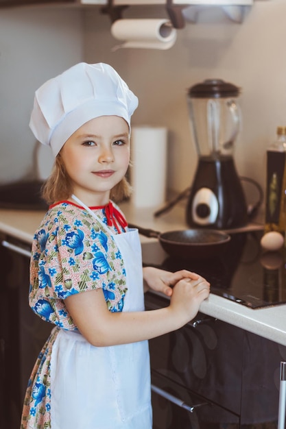 La chica cocinera está parada cerca de la estufa Foco suave