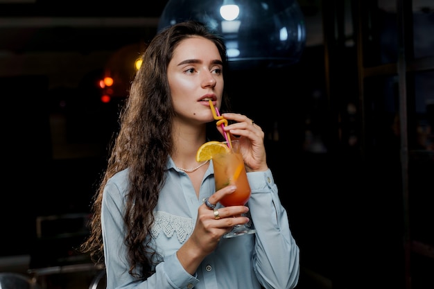 Chica con cóctel está bebiendo en el club nocturno antes de la fiesta