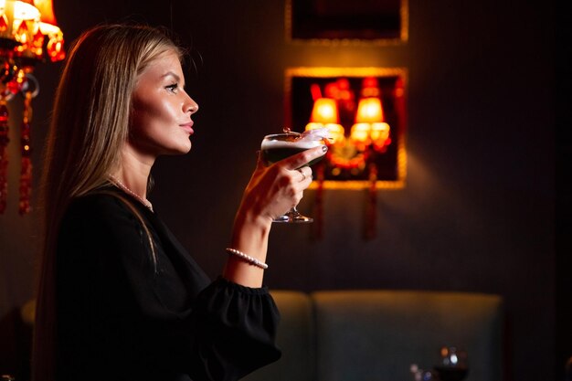 Una chica con un coctel en sus manos.