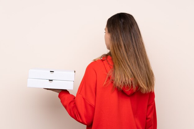 Chica cogiendo cajas de pizza sobre pared aislada