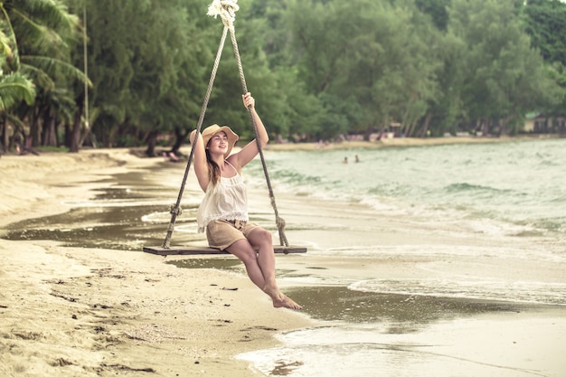 Chica en un columpio en la playa de Tailandia