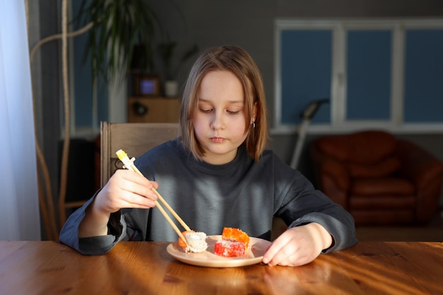 Chica come rollos de sushi en la mesa