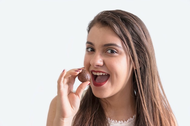 Chica comiendo chocolate con fondo blanco.