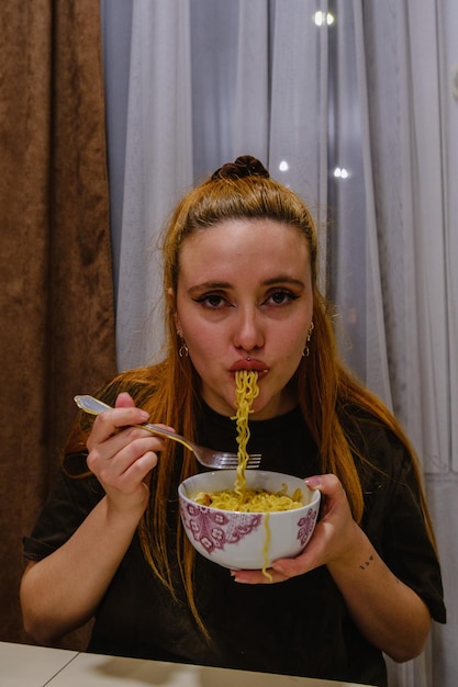 Chica comiendo fideos asiáticos