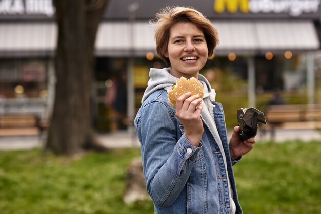 Chica comiendo una hamburguesa con comida rápida