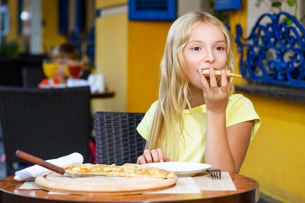 Chica comiendo pizza en la pizzería