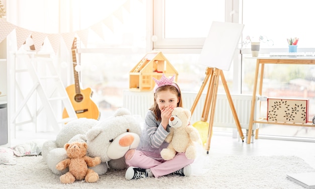 Chica compartiendo secretos con osito de peluche