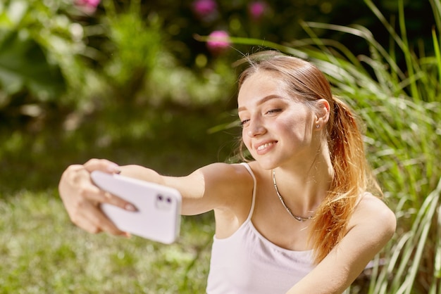 Chica se comunica en línea por teléfono en la naturaleza chat en línea en la naturaleza