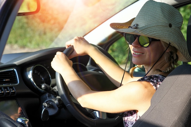 Chica conductora con gafas de sol conduciendo un coche en la carretera