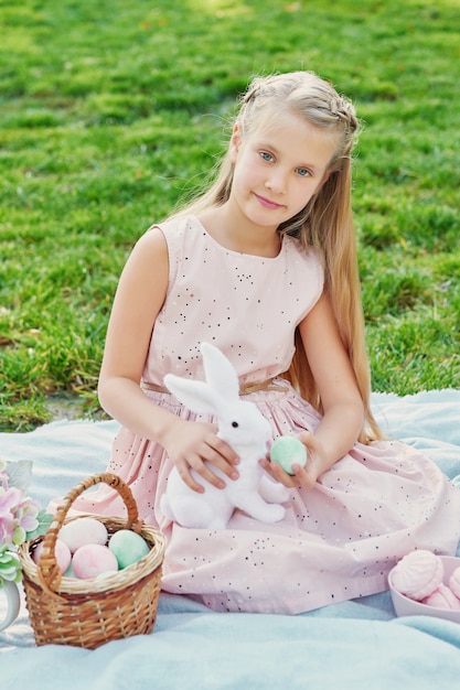 Chica con conejo y huevos de pascua en el parque sobre hierba verde